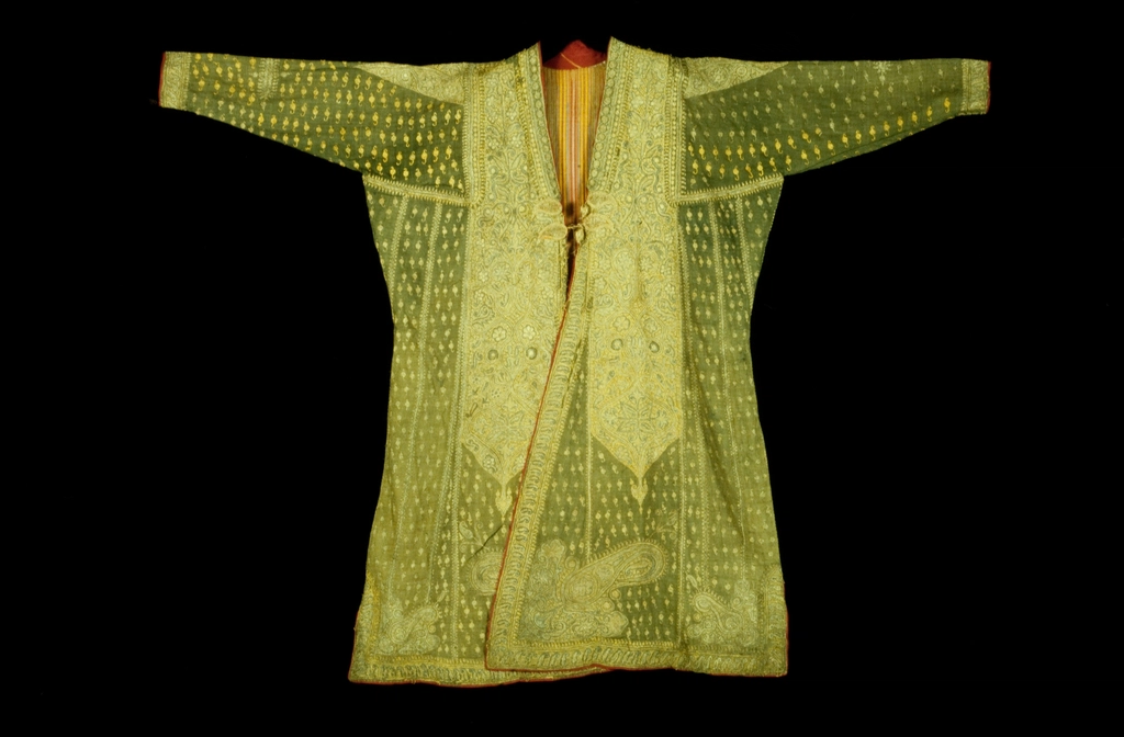 Cappotto di lana scuro appeso a un gancio accanto a una sciarpa piegata