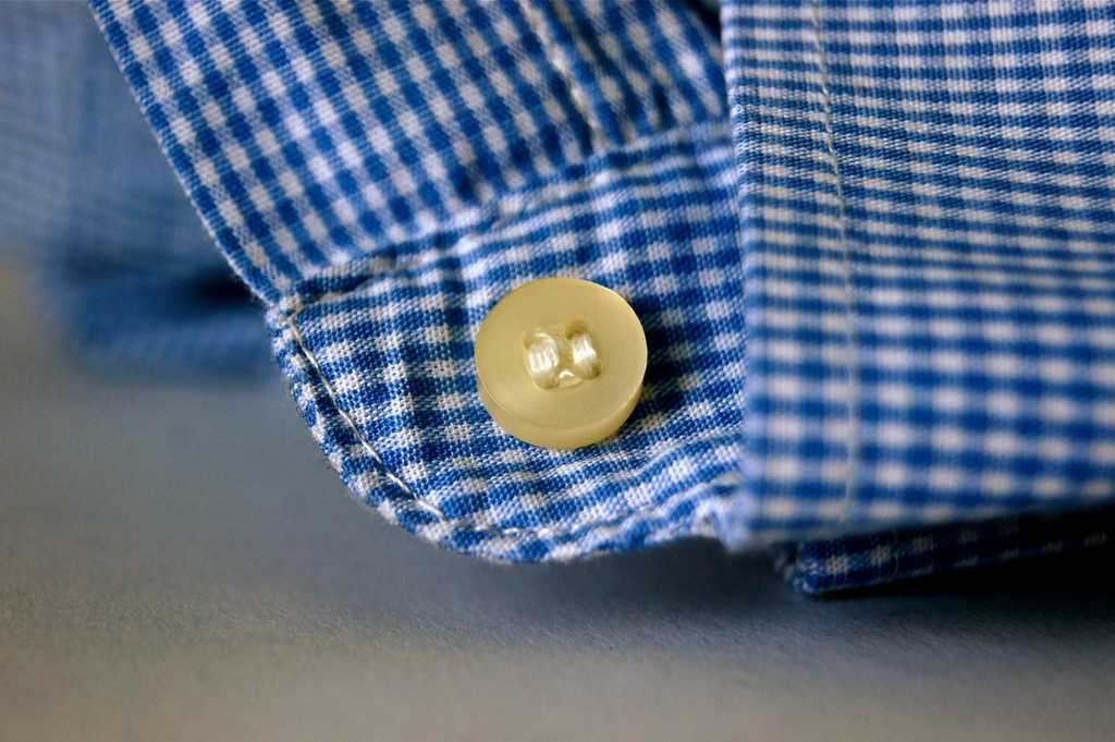 Bottoni bianchi cuciti sulla chiusura di una camicia, ripresi molto da vicino