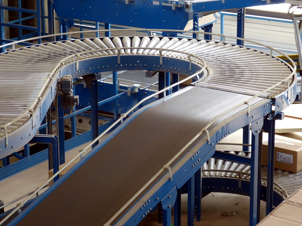 Nastro trasportatore industriale con materiale sparso che scorre dentro un capannone