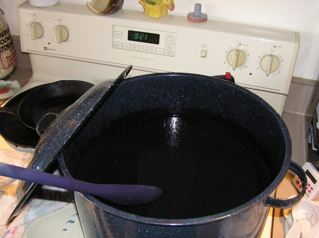Pentola in acciaio sul fornello con un tessuto immerso in un bagno di colore scuro