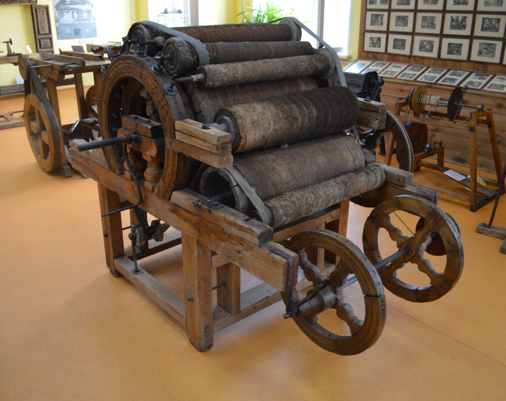 Carda industriale con cilindri rivestiti che distendono un velo di fibre di lana